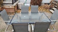 Full view of glass top table and six mesh chairs on brick patio