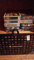 Stack of boxed jigsaw puzzles inside black storage bag with colorful puzzle piece pattern