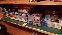 Shelves holding multiple boxed puzzles showcasing a mix of Ravensburger and other brands with varying piece counts.