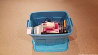 Blue plastic tote with a pink organizer inside showing scrapbooking papers and some clips on top