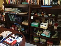Photo showing two dark wood bookcase bottoms filled with books and miscellaneous items to illustrate size and condition