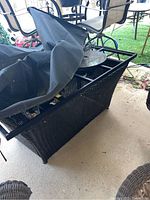 Side angle showing the metal frame top and black faux wicker base with propane tank inside beneath the table.