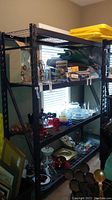 Front side view of large metal shelving unit holding various household items.