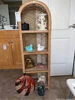 Front view of 4-tier rattan shelf with various decorative items on and around it, showing overall design and size.