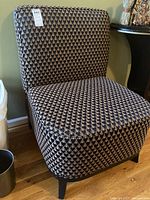 Front and side view of a side chair upholstered in dark fabric with a geometric triangular pattern, showing seat, backrest, and dark wooden legs.