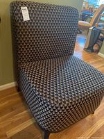 Side chair showing backrest and upper seat with geometric pattern upholstery and price tag.