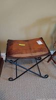 Front angle of the stool showing distressed brown leather seat and metal legs with curled foot design.