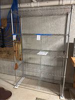 5 tier metal wire shelving unit standing assembled in basement with concrete wall background.