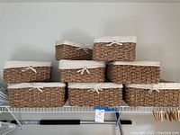 Front view of all eight braided baskets on a white wire shelf showing size variation and liner detail.