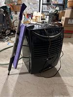 Side view showing dehumidifier and purple Snow Joe shovel leaning against it in a basement.