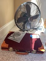 Hunter oscillating fan showing full front view with backgammon game case and fan manual in foreground, demonstrating set contents.