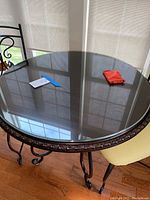 Top view of the Pier One bistro table showing the glass top and notes and red pouch resting on the surface.