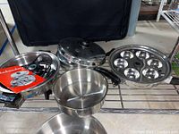 Cookware set displayed on a shelf showing electric skillet, double boiler, large pot, and muffin pan