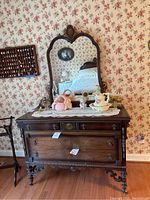 Full front view of Victorian style wooden dresser with attached mirror, tabletop decor, shows dresser shape, hardware and mirror crest