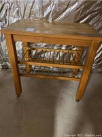 Pine work table full front view showing wooden top, legs, and lower shelves on wheels.