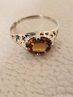 Front view of ring showing oval amber-colored gemstone and prong setting