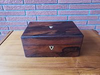 Front view of the closed rosewood box highlighting wood grain and keyhole.