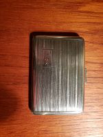 Front side of the closed antique sterling silver cigarette case showing monogram and linear pattern.