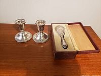 Pair of sterling silver candlesticks and sterling brush in fitted case on wooden surface
