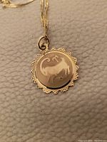 Front view of circular pendant with engraved bull motif and scalloped edge