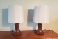 Two teak lamps unlit, front view on wood surface