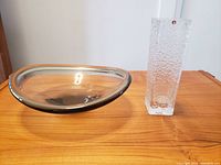 Clear textured rectangular vase with Iittala Finland red label and Holmegaard signed clear glass bowl on wooden surface