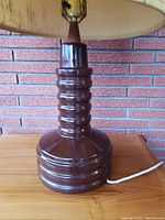 Close-up of the ribbed dark brown glazed ceramic base of the lamp showing texture and finish.