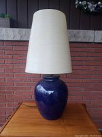 Full view of lamp showing blue ceramic base and tall off-white shade