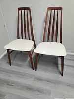 Front view of both teak chairs with white seats side by side