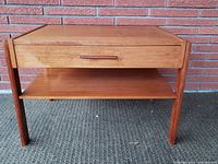 Front view of the teak side table showing drawer and bottom shelf