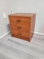 Front view of the teak small dresser showing all three drawers closed and handles visible.