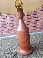 Close-up of the lamp's solid teak wood base showing its natural grain and wood finish.