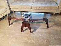 Assembled table in living room setting, view from front showing glass top and walnut base