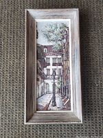 Framed narrow street scene oil painting on board by George Grunblatt.