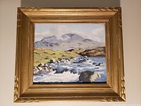 Full view of the framed oil painting landscape with a river, rocks, and mountains.