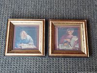 Two watercolor paintings in gold-tone frames side by side on carpet