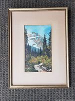 Front view of framed signed painting showing mountain landscape, pine trees, and winding path.