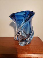 Front view of the signed Val Saint Lambert blue and clear glass vase showing its twisted, fluid shape and rich blue color at the top transitioning to clear glass at the base.