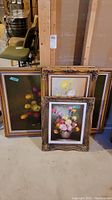 All four framed paintings arranged leaning against wall