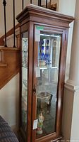 Front and left side view of wood curio cabinet showing glass door, mirror back, and wood frame.