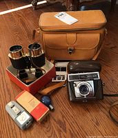 Full lot including camera with leather case, tan leather storage bag, Zeiss Ikon Ikonlitz 5 flash, bulb, booklets, and binoculars