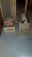 Two cardboard boxes on basement floor, one labeled Mason, other plain, containing Christmas decorations and lights, untested.