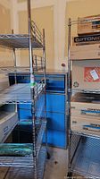 Two chrome wire shelving racks standing side by side, one loaded with boxes.