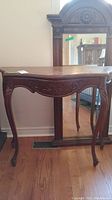 Wood hall table viewed from front, showing carved apron and cabriole legs, polished wood surface.