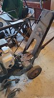Photo showing the whole rototiller unit with white Honda engine, metal frame, handles and two wheels.