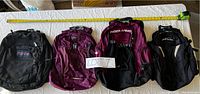 Four backpacks laid out flat with a measuring tape above them for scale, showing lot contents