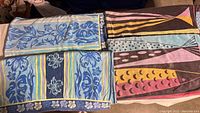 Four beach towels laid out showing two distinct designs: blue/yellow floral and pink/yellow fish motifs.