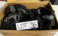Black and gray Explorer brand backpack in a cardboard box, showing its collapsed form with visible pockets and belts.