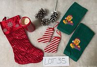 Red Christmas stocking, red candle, two red and white striped fabric ornaments, two green towels embroidered with Winnie the Pooh with Santa hat
