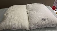 Two standard pillows side by side, one a Beautyrest Black pillow, both with beige pillowcases visible.